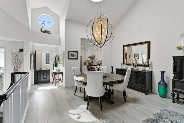 dining space featuring high vaulted ceiling, a chandelier, and light wood-type flooring