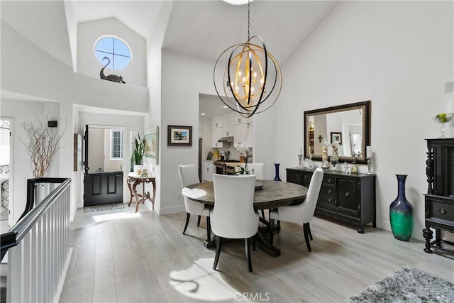 dining area with light wood-style floors, baseboards, high vaulted ceiling, and an inviting chandelier