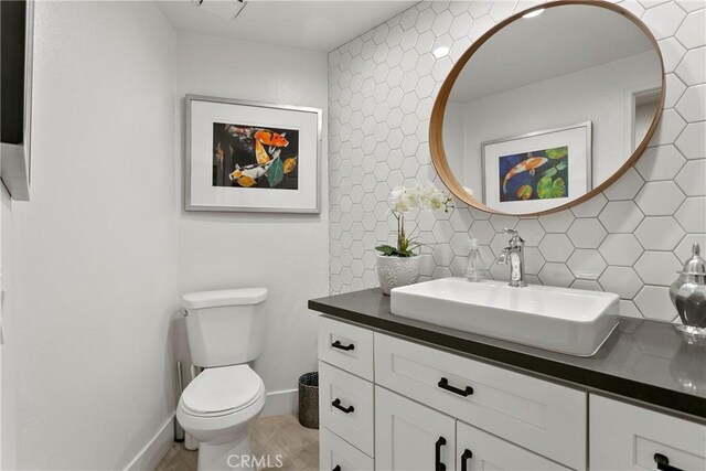 bathroom featuring toilet, tile walls, backsplash, and vanity