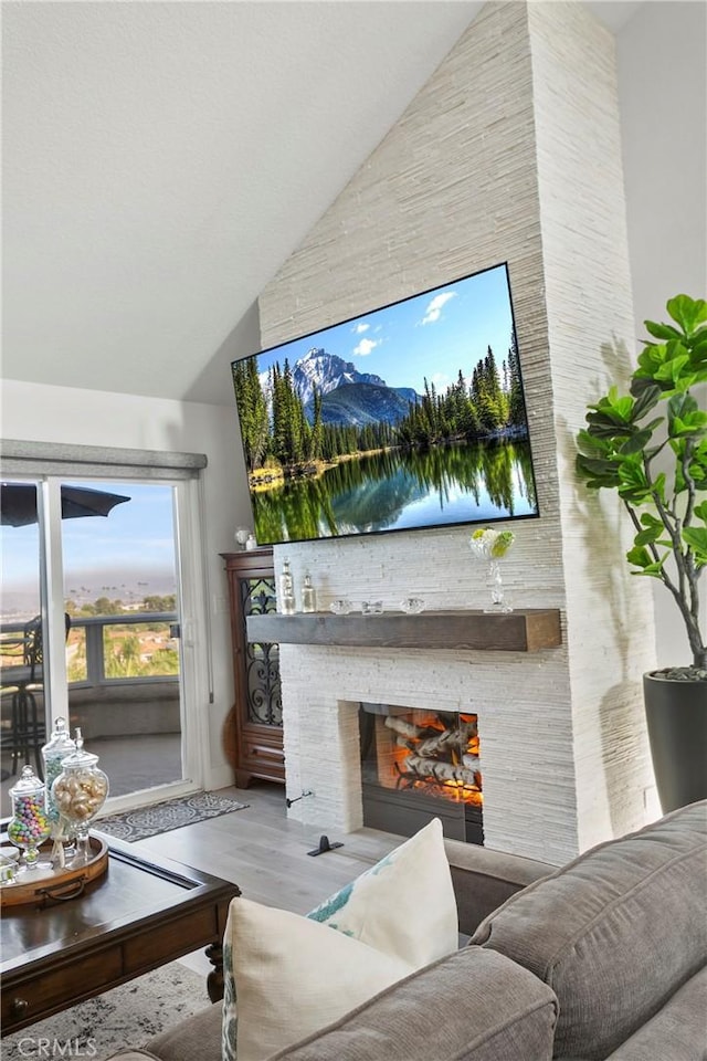 living room with high vaulted ceiling, light wood-type flooring, and a fireplace