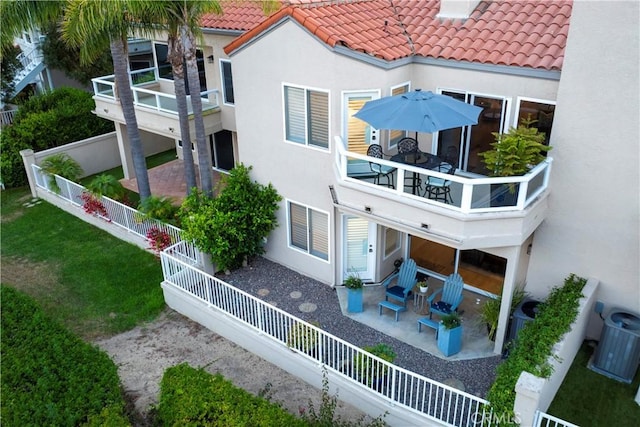 rear view of house featuring a lawn, central AC unit, a patio area, and a balcony