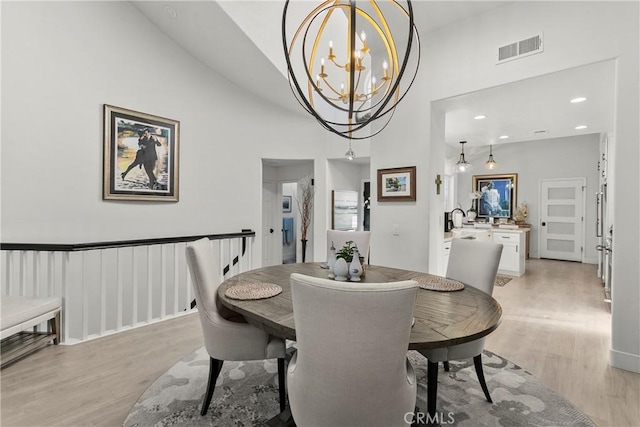 dining room featuring high vaulted ceiling, light hardwood / wood-style flooring, and an inviting chandelier