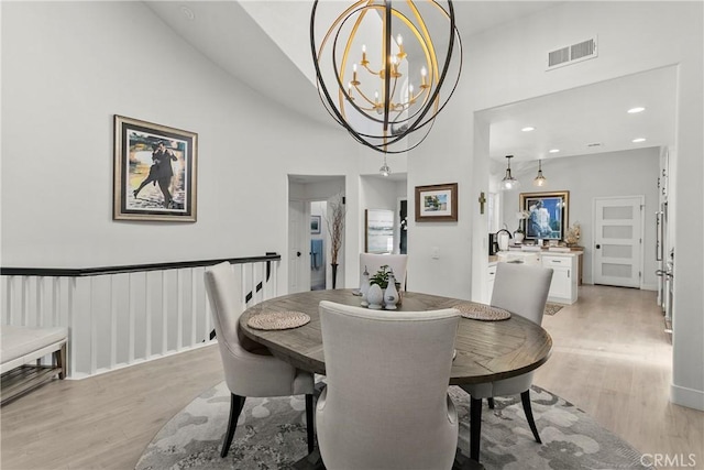 dining room featuring light wood finished floors, recessed lighting, visible vents, a high ceiling, and a chandelier