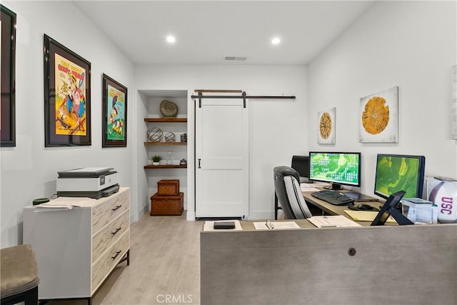 office area featuring light wood-type flooring, a barn door, visible vents, and recessed lighting