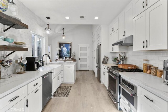 kitchen featuring pendant lighting, white cabinetry, decorative backsplash, sink, and high quality appliances