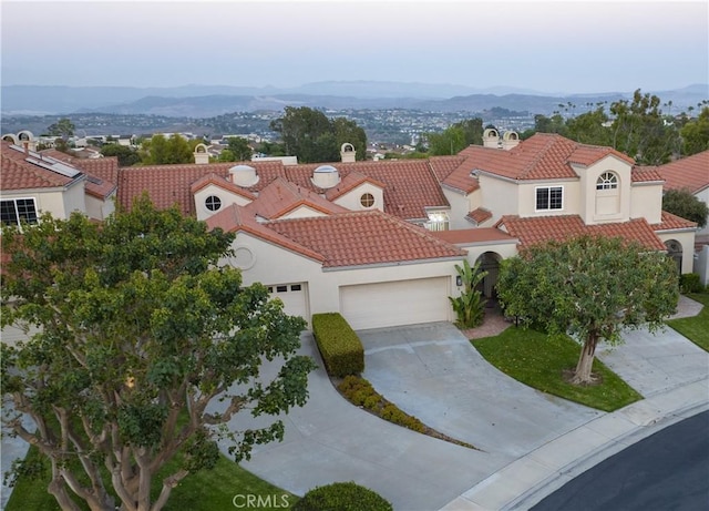 view of front facade featuring a tiled roof, an attached garage, and a mountain view