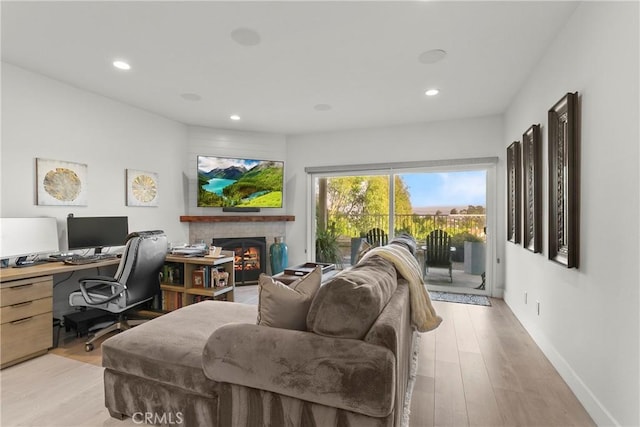 office space with baseboards, a lit fireplace, light wood-type flooring, and recessed lighting