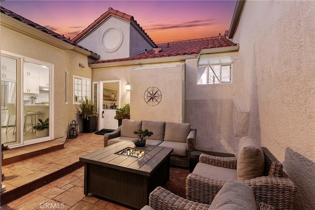 patio terrace at dusk with an outdoor living space with a fire pit