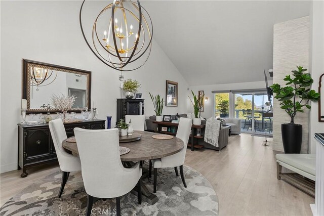 dining area featuring high vaulted ceiling, light hardwood / wood-style floors, and a chandelier