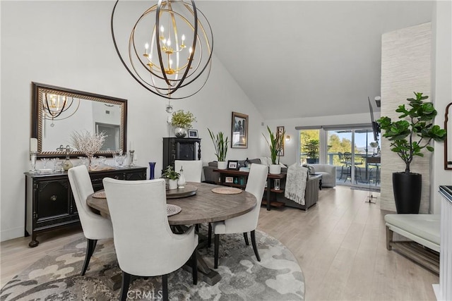 dining area featuring high vaulted ceiling, light wood finished floors, and an inviting chandelier