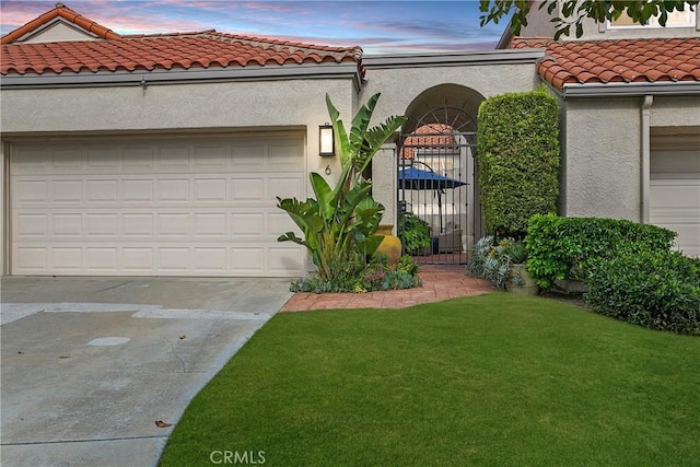 view of front of home featuring stucco siding, an attached garage, a front yard, driveway, and a tiled roof