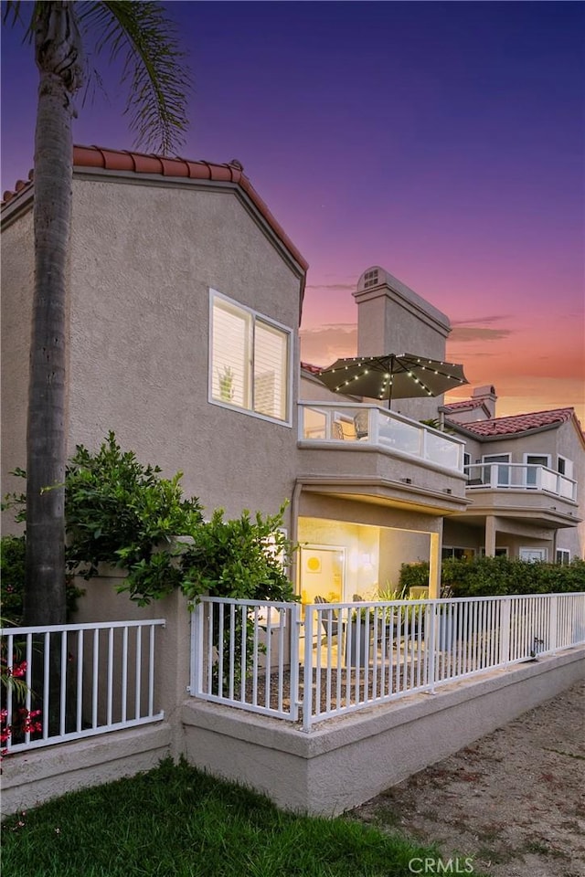 back of property with a balcony and stucco siding