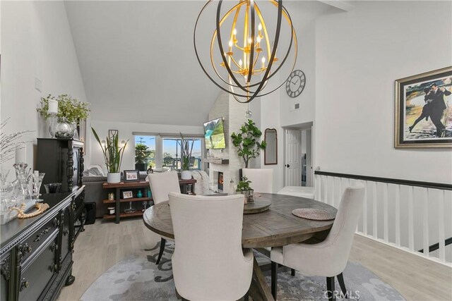 dining area with an inviting chandelier, light hardwood / wood-style floors, and high vaulted ceiling