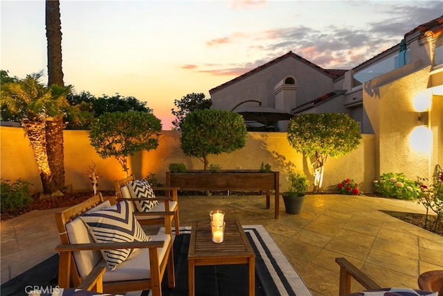 patio terrace at dusk featuring a fenced backyard