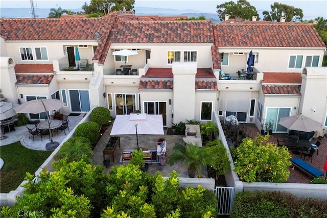 back of property with outdoor dining area, a patio, stucco siding, and a tiled roof