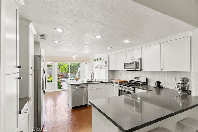 kitchen with visible vents, a peninsula, appliances with stainless steel finishes, and a textured ceiling