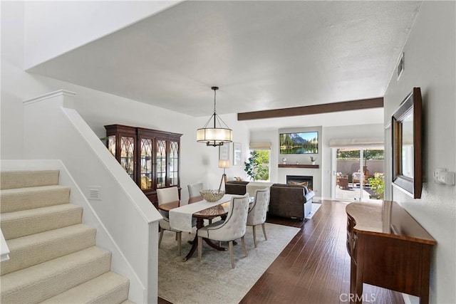 dining space featuring an inviting chandelier, a fireplace, stairway, visible vents, and dark wood-type flooring