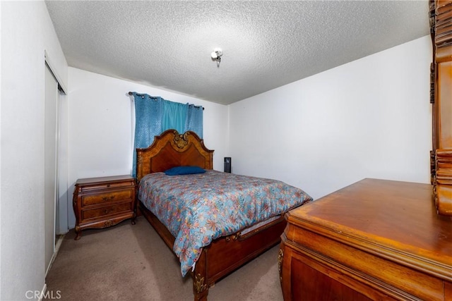 bedroom featuring a textured ceiling, a closet, and light carpet