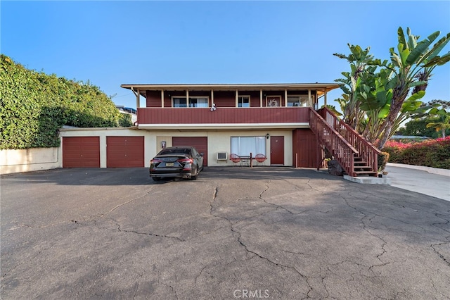 view of front facade featuring a garage, stairway, and aphalt driveway