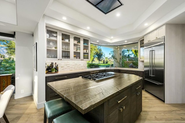 kitchen with white cabinetry, a breakfast bar area, appliances with stainless steel finishes, dark brown cabinets, and a kitchen island