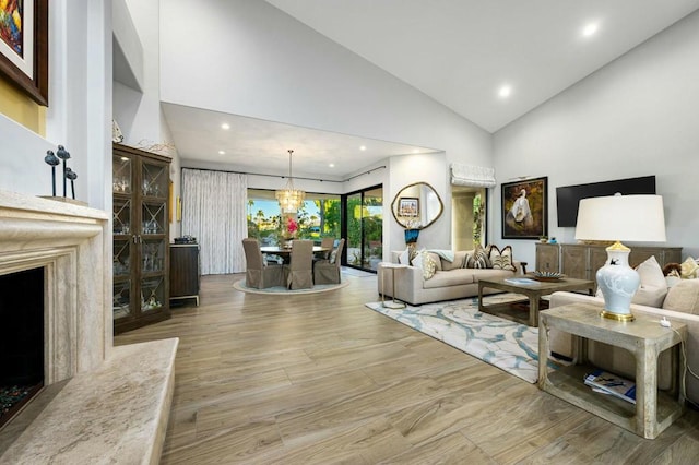 living room with high vaulted ceiling, a chandelier, and light hardwood / wood-style flooring