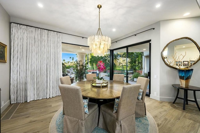 dining space with light hardwood / wood-style flooring and a notable chandelier