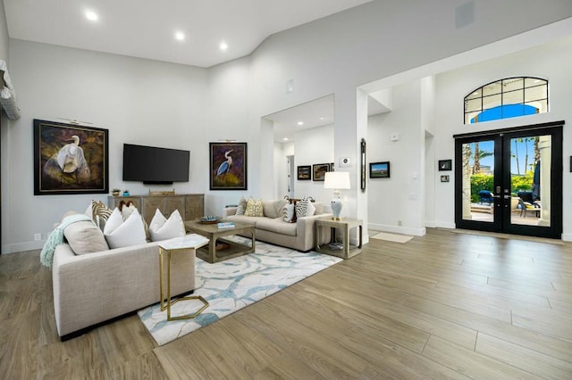 living room with french doors, a high ceiling, and light hardwood / wood-style flooring