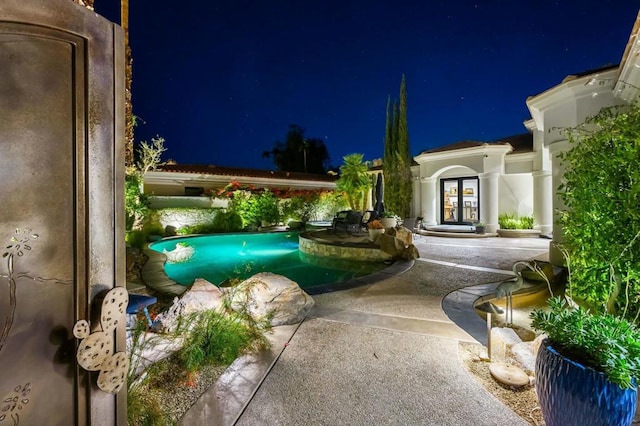 pool at night with a patio area