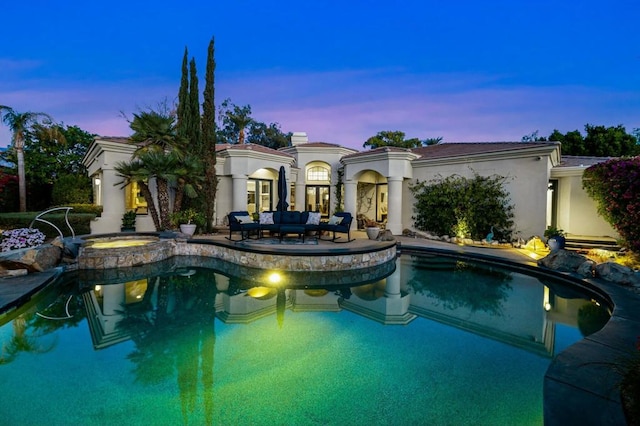 pool at dusk with an outdoor hangout area, an in ground hot tub, and a patio