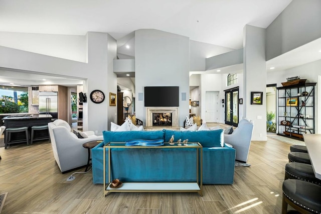 living room featuring high vaulted ceiling and light wood-type flooring