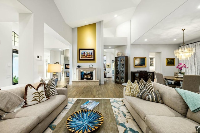 living room featuring high vaulted ceiling, wood-type flooring, a multi sided fireplace, and an inviting chandelier