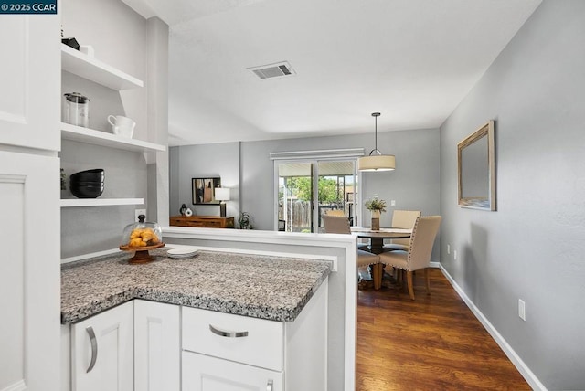 kitchen featuring decorative light fixtures, light stone counters, white cabinetry, and dark wood-type flooring