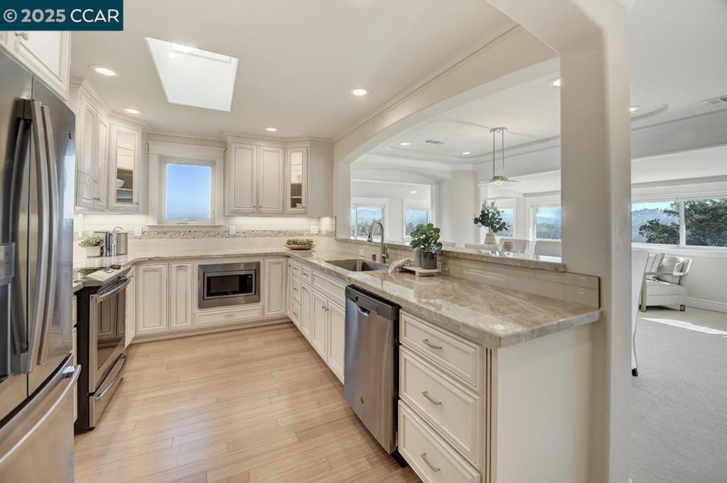 kitchen with decorative light fixtures, sink, white cabinetry, light stone countertops, and stainless steel appliances