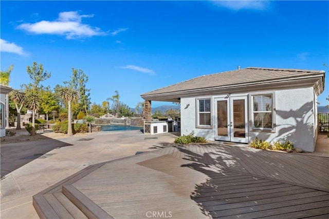 wooden deck featuring an outdoor kitchen, french doors, and a patio