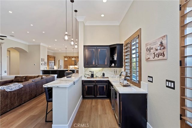 bar featuring light hardwood / wood-style floors, decorative backsplash, pendant lighting, light stone countertops, and crown molding