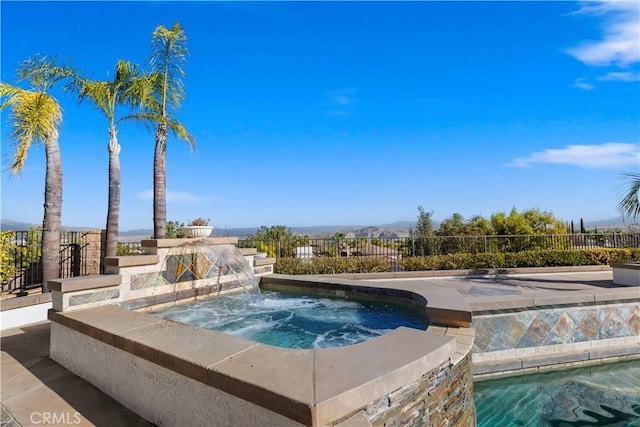 view of pool featuring pool water feature and an in ground hot tub