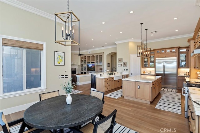 dining space with light wood-type flooring, ceiling fan, crown molding, and sink