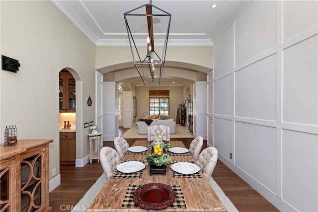 dining room with dark wood-type flooring, ornamental molding, and a chandelier