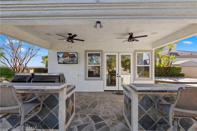 view of patio with ceiling fan, area for grilling, and a bar