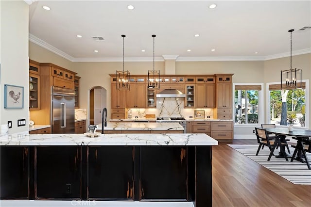 kitchen featuring light stone counters, decorative light fixtures, crown molding, and high end appliances