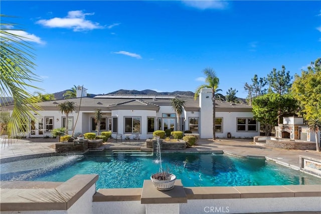 exterior space with a patio area, exterior fireplace, and pool water feature