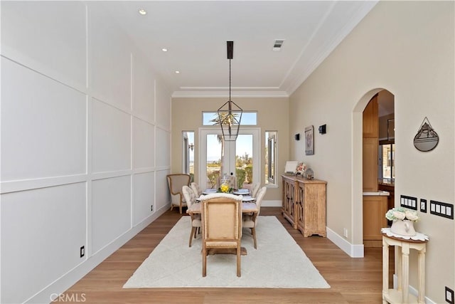 dining space featuring ornamental molding, light hardwood / wood-style floors, and french doors