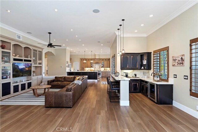 living room with wine cooler, ceiling fan, crown molding, and wood-type flooring