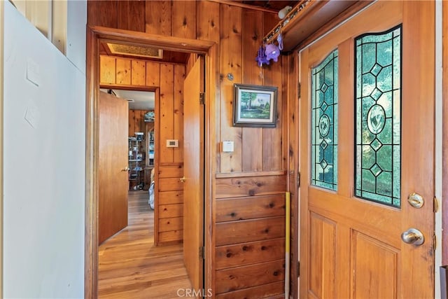 entrance foyer with light wood-type flooring, plenty of natural light, and wooden walls