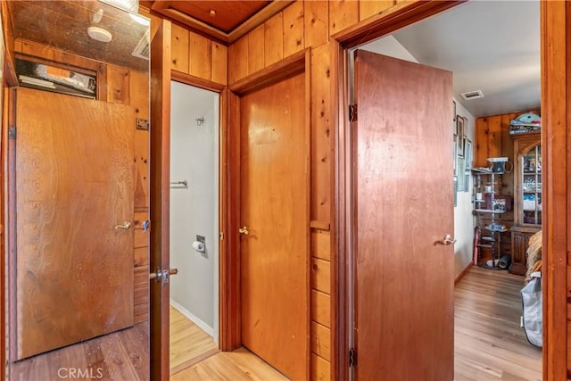 hallway with wood walls and light hardwood / wood-style floors