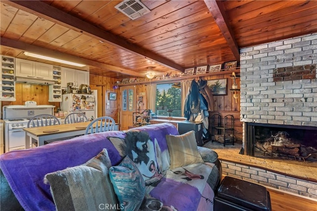 living room featuring wood ceiling, wood walls, light wood-type flooring, a fireplace, and beam ceiling