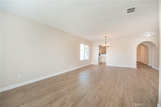 unfurnished living room featuring a chandelier and light hardwood / wood-style flooring