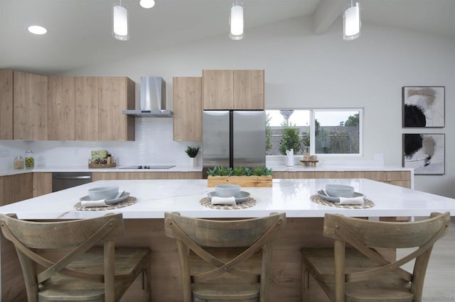 kitchen featuring stainless steel appliances, decorative light fixtures, lofted ceiling with beams, and wall chimney range hood