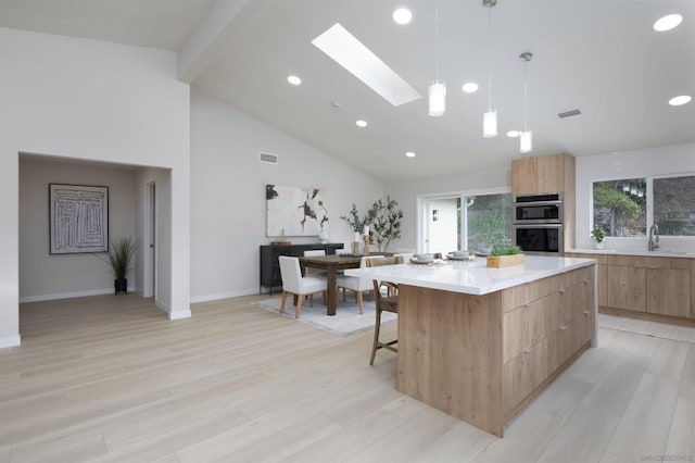 kitchen featuring decorative light fixtures, a center island, sink, a skylight, and double oven