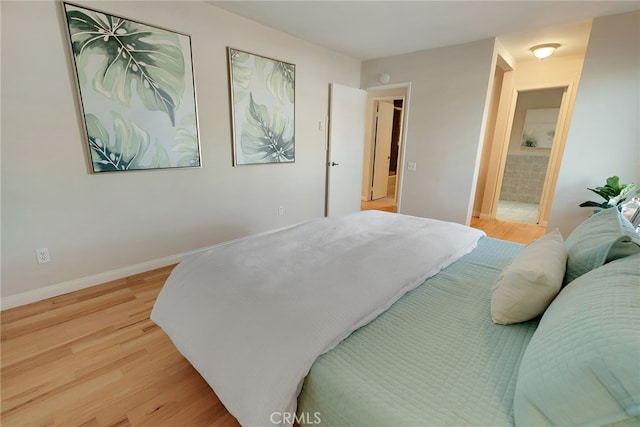 bedroom with light hardwood / wood-style floors and ensuite bath